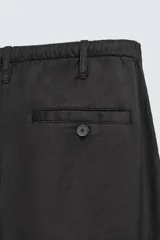 Pantalón de corte regular fit confeccionado en mezcla de algodón y lino. Presenta cintura elástica con cordón ajustable, cierre frontal con cremallera y botón, bolsillos laterales y bolsillo trasero de vivo con botón.