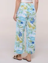 Pantalón crop de lino y rayón, con diseño wide leg de corte holgado, estampado tropical de hojas en tonos verde, azul y marrón sobre fondo blanco. Cuenta con pretina trasera elastizada y bolsillos delanteros.