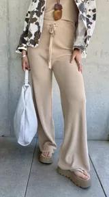 Pantalón de punto color beige, de corte ancho y tiro alto, con cintura elástica y cordón ajustable.