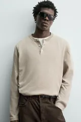Jersey relaxed fit de punto en hilatura con mezcla de algodón y cashmere. Presenta cuello redondo con cierre frontal de botonadura y manga larga.