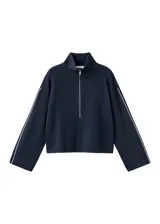 Jersey de punto color negro, con cuello polo y cierre frontal de cremallera, mangas largas y detalles de ribetes claros en las costuras.