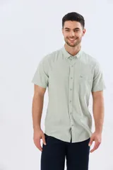 Camisa de manga corta confeccionada en mezcla de lino y algodón, color beige, con cuello camisero abotonado, bolsillo frontal en el pecho y cierre de botones.