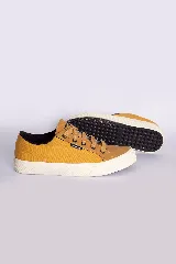 Zapatillas casuales color mostaza con cordones negros y suela blanca.