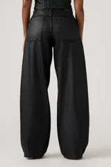 Pantalón de jean con acabado encerado negro, de corte super baggy y silueta tipo barril, con diseño de cinco bolsillos y cierre frontal con botón y cremallera.