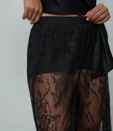 Pantalón de encaje negro con diseño aladín, de corte amplio y fluido con cintura elástica. Presenta una estructura transparente en las piernas y forro corto en la parte superior.