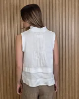 Musculosa marrón sin mangas, con cuello alto, escote en V y detalles de pespuntes blancos en contraste. Presenta pliegues y alforzas frontales.