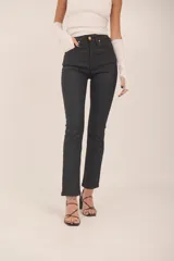 Jean de tiro alto color negro con acabado encerado, silueta slim y pierna levemente evasé.