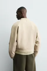 Sudadera de corte cropped confeccionada en tejido técnico compacto de algodón con elasticidad. Presenta cuello subido con cierre frontal de cremallera, manga larga y acabados en rib del mismo tejido.