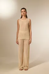 Top sin mangas color dorado, confeccionado en tejido de punto abierto con lentejuelas, cuello redondo a la base y diseño holgado.