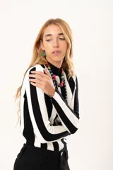 Polera de tejido de punto con diseño de rayas verticales anchas en blanco y negro, cuello alto y manga larga.