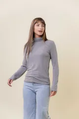 Polera de manga larga en color crudo, confeccionada en tejido suave y liviano con leve elasticidad. Presenta un cuello alto tipo tortuga y un calce regular, ideal para usar como prenda base o sola.