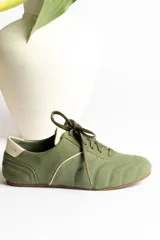 Zapatillas bajas color crema con cordones y suela marrón.