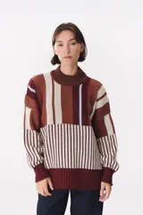 Buzo de tejido de punto con diseño de rayas verticales combinadas en tonos tierra, bordó y detalles en celeste. Presenta cuello alto, corte oversize y terminaciones en rib en puños y ruedo.