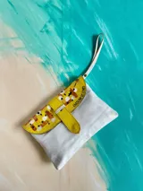 Sobre de mano de cuero blanco y amarillo, con solapa texturizada tipo cocodrilo y detalle de arte pintado a mano. Cuenta con cierre de broche imán y tira de mano.
