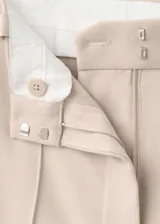 Pantalón de vestir de tiro medio, color beige, de corte recto y amplio con pinzas frontales.