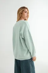 Buzo de tejido de punto en color blanco, con cuello redondo, mangas largas y corte holgado.