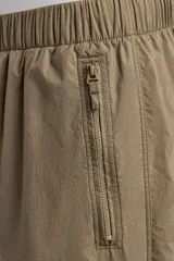 Pantalón jogger de corte regular confeccionado en tejido técnico ligero, con cintura elástica, bolsillos laterales con cierre y puños elásticos en los tobillos.