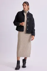 Vestido midi de punto canale color beige, con cuello alto y mangas largas, de corte recto y ajustado.