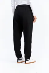 Pantalón tipo jogger de tiro medio con cintura elastizada y puños en los tobillos. Confeccionado en tejido de algodón y poliéster, presenta un diseño liso y holgado.