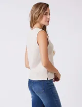 Buzo sin mangas color beige, de tejido melange suave, con cuello a la base y sisas amplias. Presenta pequeños tajos en el ruedo para una mejor caída.