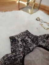 Body de manga larga y cuello alto, confeccionado en microtul estampado con diseño animal print abstracto. Presenta una espalda descubierta y cierre con broches en la entrepierna.