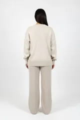 Pantalón tipo palazzo de tiro alto en color beige, confeccionado en tejido de punto con costura central vertical en el frente.