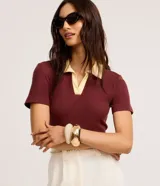 Blusa de manga corta confeccionada en tejido acanalado de algodón con elastano, de color bordó con cuello polo en tono amarillo claro y escote en V.