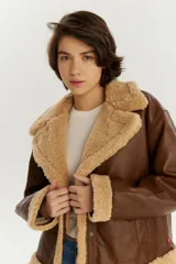 Campera de estilo aviador en color marrón, confeccionada en cuero sintético con interior y detalles de corderito en color beige en cuello, puños y ruedo.