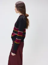 Sweater clásico de punto cable con cuello redondo a la base, mangas largas y fit al cuerpo. De color marrón con franjas horizontales violetas y amarillas, cuenta con el cuello, puños y ruedo acanalados, además de un pequeño logo bordado en el pecho.