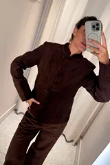 Chaqueta de gamuza color marrón oscuro, con cuello mao, cierre frontal de botones y diseño entallado.