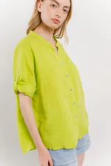 Camisa de lino color verde lima, de calce relajado, con cuello mao, botones al frente y bolsillo en el pecho. Las mangas son cortas y pueden usarse arremangadas.