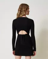 Remera negra de punto con textura acanalada, cuello redondo y mangas largas. Presenta un lazo en la cintura que se ata en la espalda.