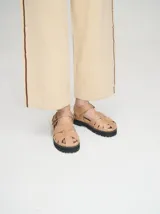 Sandalias romanas de cuero tostado, estilo chunky con plataforma y suela tractora de goma negra. Cuentan con tiras cruzadas en el empeine y tira ajustable con hebilla metálica en el tobillo.