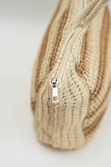 Bolso tipo tote de tejido trenzado en tonos beige y marrón, con diseño de rayas horizontales y doble asa de hombro.