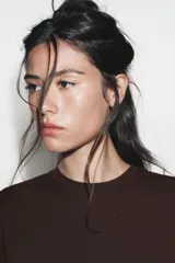 Vestido largo color marrón oscuro, con cuello redondo, manga corta y detalle de drapeado fruncido en el lateral izquierdo, terminando en línea evasé.