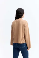 Remera de manga larga color beige, con cuello redondo y estampa gráfica frontal en color celeste.