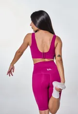 Conjunto deportivo compuesto por un top de escote redondo con logo estampado y calza corta tipo biker de tiro alto, confeccionado en tela técnica elástica.