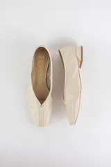 Mocasines de cuero color beige con costura central en la capellada y taco bajo.