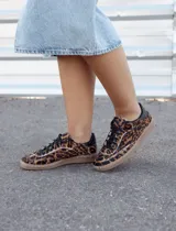 Zapatilla urbana de cuero con pelo estampado animal print de leopardo. Presenta cordones negros, detalle de cuero negro en el talón y suela cosida de goma en color tostado.