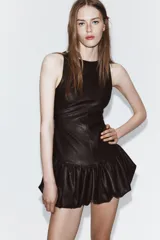 Vestido corto de Zara con efecto piel, cuello barco y diseño sin mangas. Presenta un bajo abullonado con elástico interior y cierre de cremallera en la espalda.