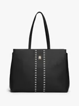 Cartera tipo tote de Tommy Hilfiger en color negro, confeccionada en poliuretano con textura granulada. Presenta doble asa superior, cierre principal y un diseño central decorativo con tachas metálicas y el logo monograma TH en metal dorado.