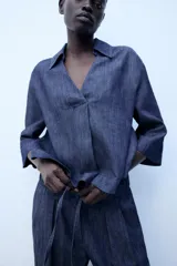 Camisa de lino azul, con cuello solapa, escote en V y mangas por debajo del codo.