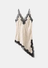 Top de poliéster color crudo con estampado de lunares negros, diseño asimétrico con detalles de puntilla negra en el escote y el ruedo.