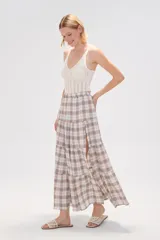 Falda larga de algodón con diseño a cuadros en tonos beige, blanco, marrón y celeste. Presenta un diseño escalonado con volados y una abertura lateral pronunciada.