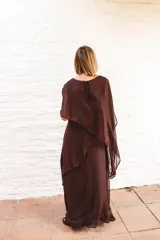 Vestido largo de gasa color bordó, con diseño de capas superpuestas y terminaciones en picos diagonales. Presenta mangas tipo capa que cubren sutilmente los brazos, brindando elegancia y libertad de movimiento.