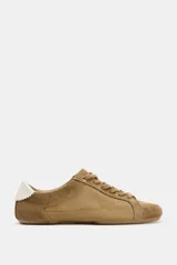 Zapatilla estilo blucher de diseño deportivo, confeccionada en una combinación de materiales lisos y gamuzados en tonos tostados, con detalle de talón en color blanco y cierre mediante cordones.