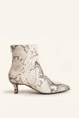 Botín blanco con estampado de piel de serpiente, punta fina y taco chupete. Cierre con cremallera en la parte trasera.