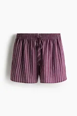 Short holgado de tela liviana color morado con finas rayas verticales blancas. Presenta cintura elástica fruncida con cordón ajustable y bajo redondeado con aberturas laterales.