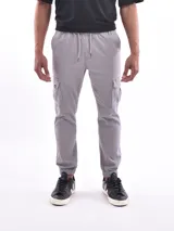 Pantalón tipo jogger cargo color gris, con cintura elástica ajustable mediante cordón, bolsillos laterales con solapa y puños elásticos en los tobillos.