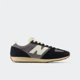 Championes New Balance modelo 471, con capellada de malla transpirable y capas de gamuza peluda en tonos negro y gris. Presenta el logo "N" en color crema y una entresuela de EVA de perfil bajo en tono beige, con suela de goma con diseño de espiga.